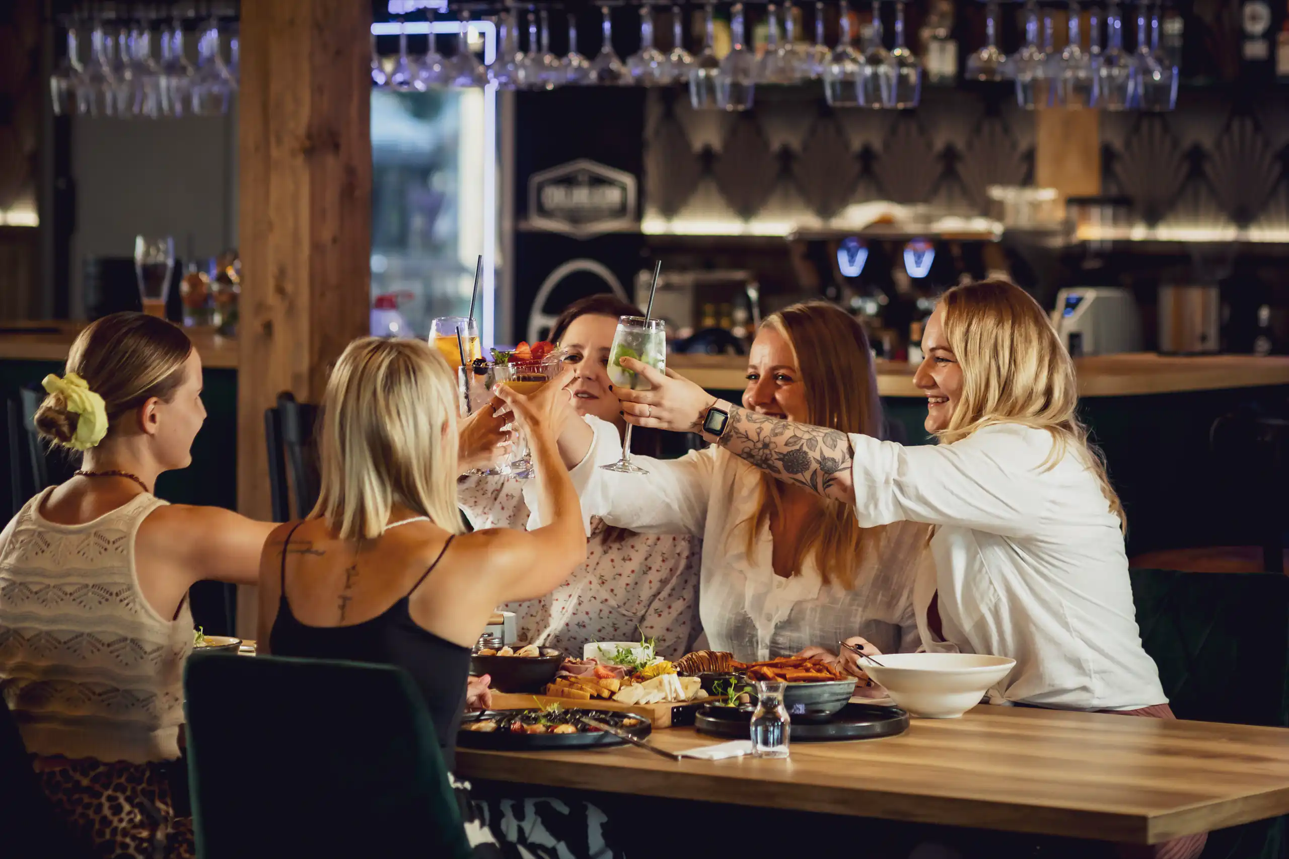 Grupa przyjaciół wznosi toast przy stole w restauracji Western Camp Resort