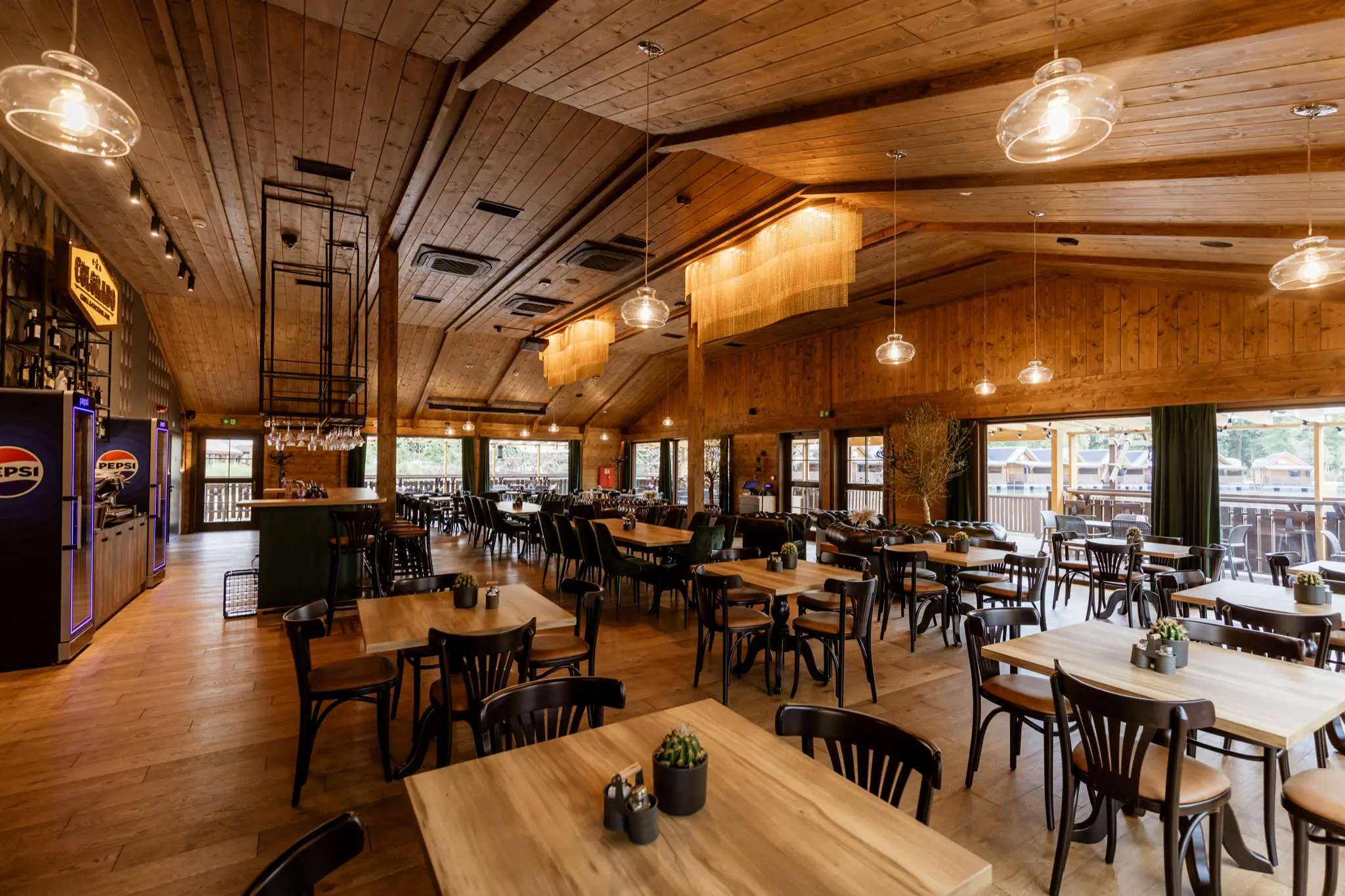 Sala Restauracji Bonanza: jasne drewno, wiszące lampy i okna z widokiem na zewnątrz